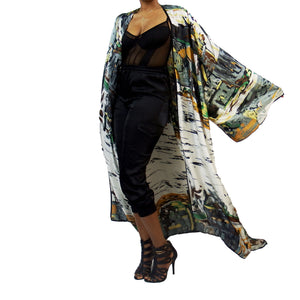 A woman models a luxury Japanese kimono robe in white with black trim, featuring subtle yellow and green tones with an abstract urban skyline design.