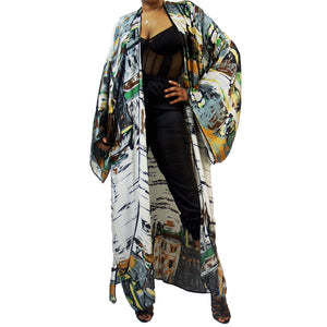 A woman models a luxury Japanese kimono robe in white with black trim, featuring subtle yellow and green tones with an abstract urban skyline design.