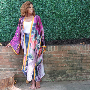 A woman models a flowing purple Japanese kimono robe adorned with flowers and golden yellow trim, fully lined for a luxurious and elegant design.