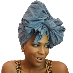 A woman models a chambray denim blue-jean African headwrap, blending classic jean style with traditional headwrap design for a stylish and comfortable look.