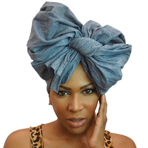 A woman models a chambray denim blue-jean African headwrap, blending classic jean style with traditional headwrap design for a stylish and comfortable look.