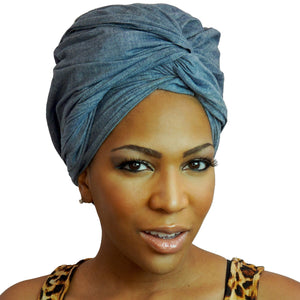 A woman models a chambray denim blue-jean African headwrap, blending classic jean style with traditional headwrap design for a stylish and comfortable look.