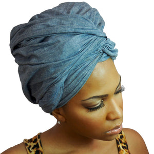 A woman models a chambray denim blue-jean African headwrap, blending classic jean style with traditional headwrap design for a stylish and comfortable look.