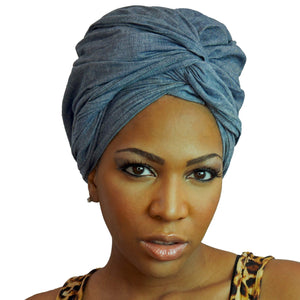 A woman models a chambray denim blue-jean African headwrap, blending classic jean style with traditional headwrap design for a stylish and comfortable look.