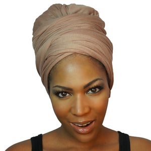 A model showcases a camel tan African headwrap in stretchy jersey knit, blending subtle elegance with a traditional design for everyday style and comfort.