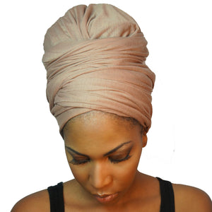 A model showcases a camel tan African headwrap in stretchy jersey knit, blending subtle elegance with a traditional design for everyday style and comfort.