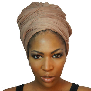 A model showcases a camel tan African headwrap in stretchy jersey knit, blending subtle elegance with a traditional design for everyday style and comfort.