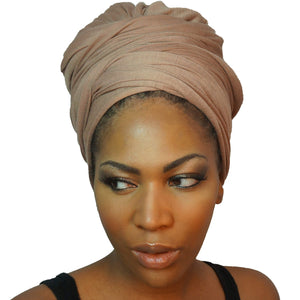 A model showcases a camel tan African headwrap in stretchy jersey knit, blending subtle elegance with a traditional design for everyday style and comfort.