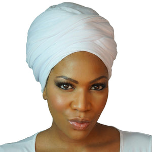 A woman models a white jersey knit stretch African headwrap, offering a comfortable and stylish look with a soft, stretchy fit perfect for any occasion.