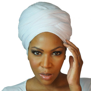 A woman models a white jersey knit stretch African headwrap, offering a comfortable and stylish look with a soft, stretchy fit perfect for any occasion.